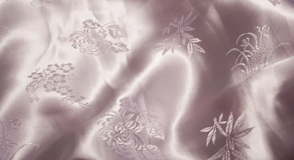 Embroidered satin duchesse fabric with lace and bead detailing